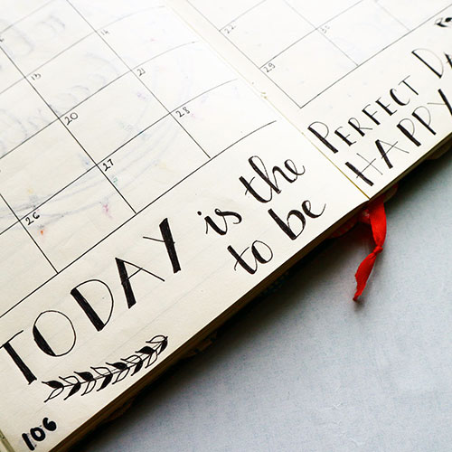 an open calendar book inscribed with Today is the Perfect Day to be Happy